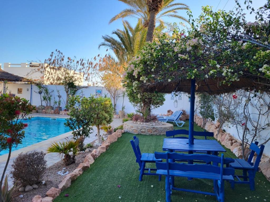 a blue table and chairs next to a swimming pool at Au jardin d’Aghir: Villa arborée, avec piscine privée sans vis à vis! in Aghīr