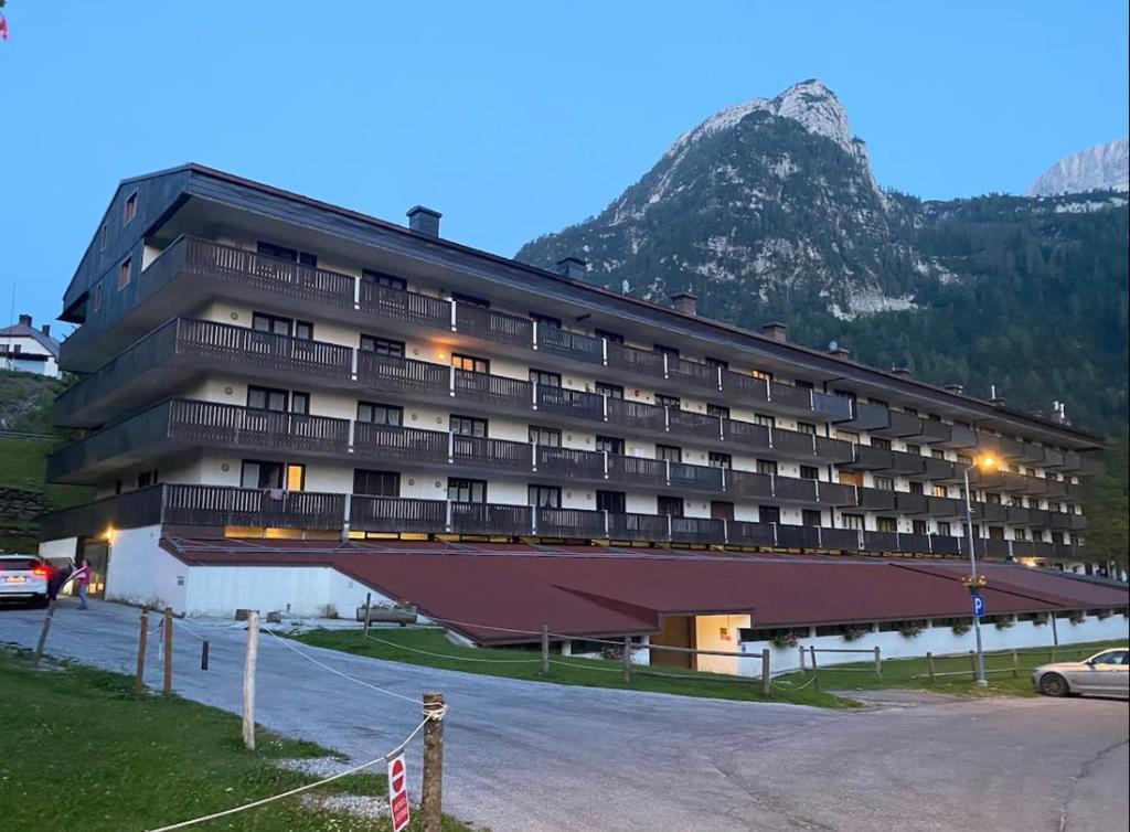 a large building with a mountain in the background at Wood apartment in Canin ski resort in Sella Nevea