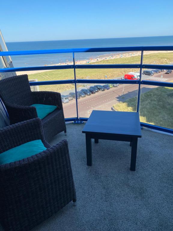 un balcón con 2 sillas, una mesa y el océano en Atlantis Appartement, en Egmond aan Zee