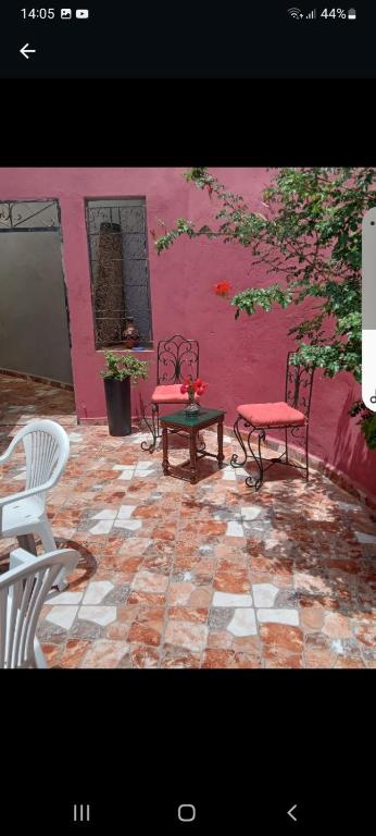 a patio with two chairs and a pink wall at Calmeplace in El Jadida