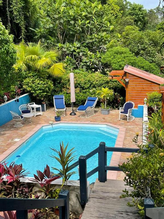 a swimming pool with two blue chairs and a house at Bas de Villa ALPINIA au Gosier in Le Gosier