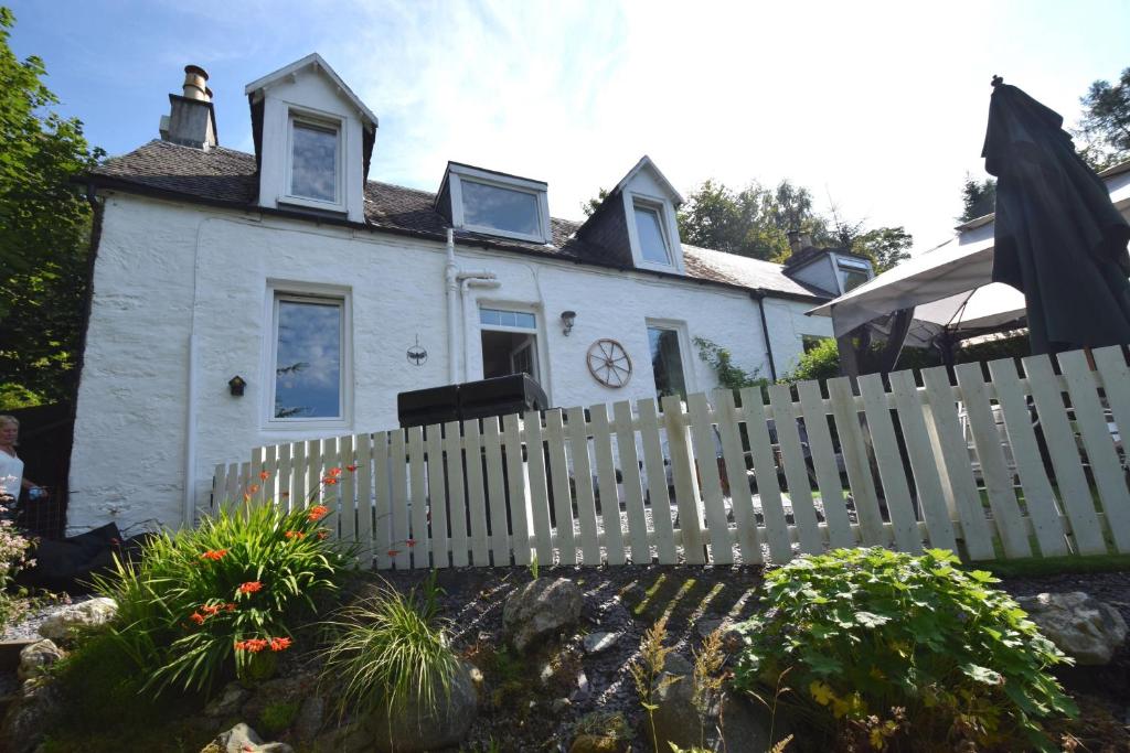 ein weißes Haus mit einem weißen Zaun davor in der Unterkunft Hollybank Cottage in Lochgoilhead