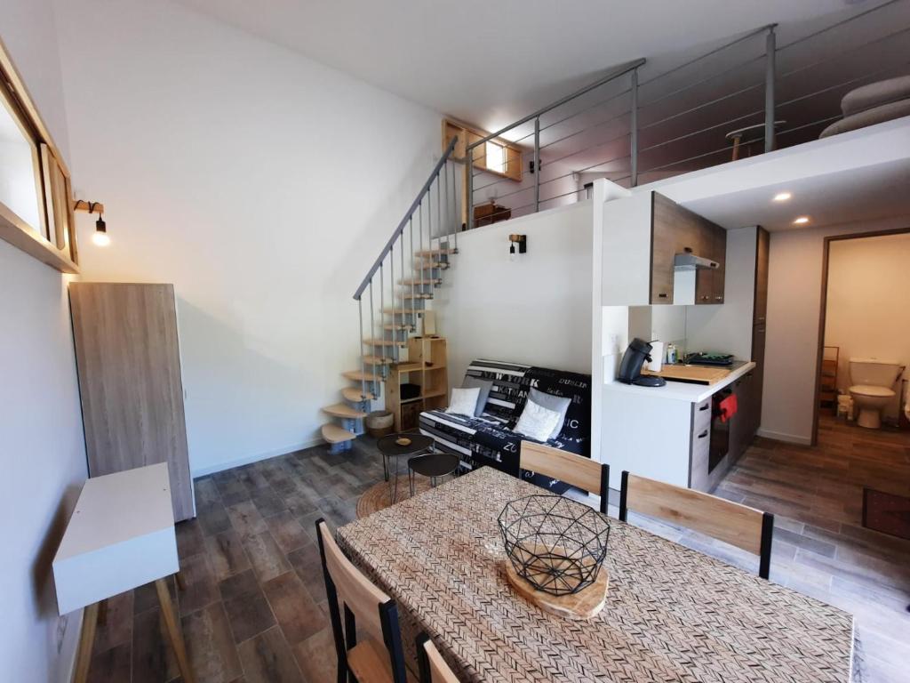 uma cozinha e sala de estar com uma mesa e uma escada em Adorable petite maison au coeur du Luberon em Villelaure