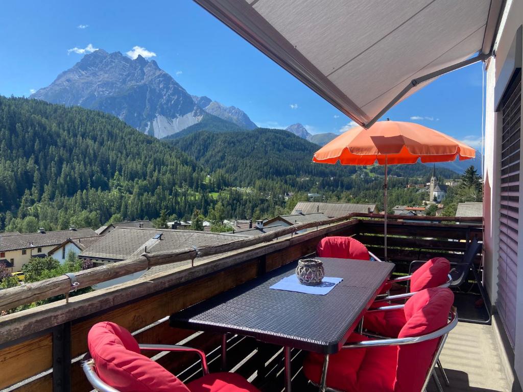 a table with chairs and an umbrella on a balcony at Ferienwohnung Sotcha 8c in Scuol
