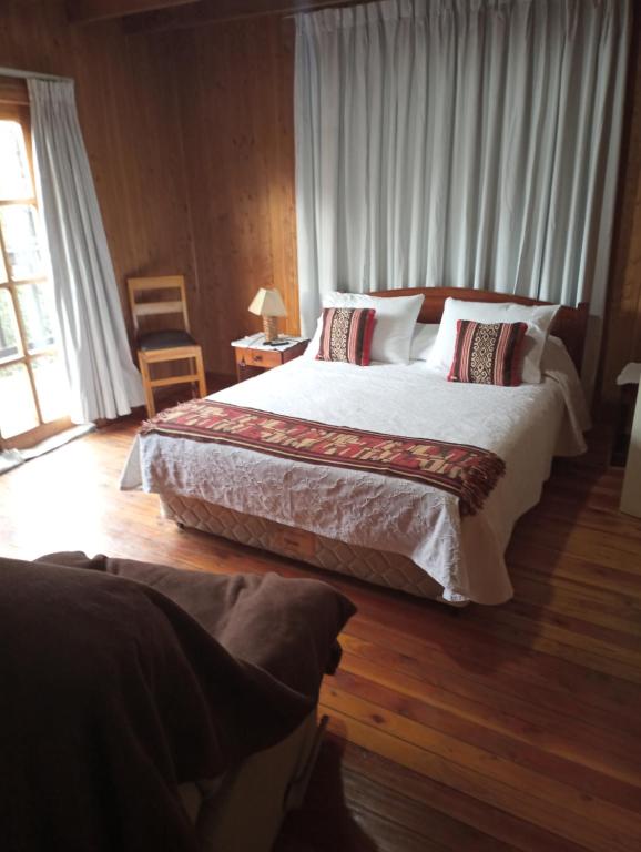 a bedroom with a large bed and a wooden floor at Omi Kika B&B in Villarrica