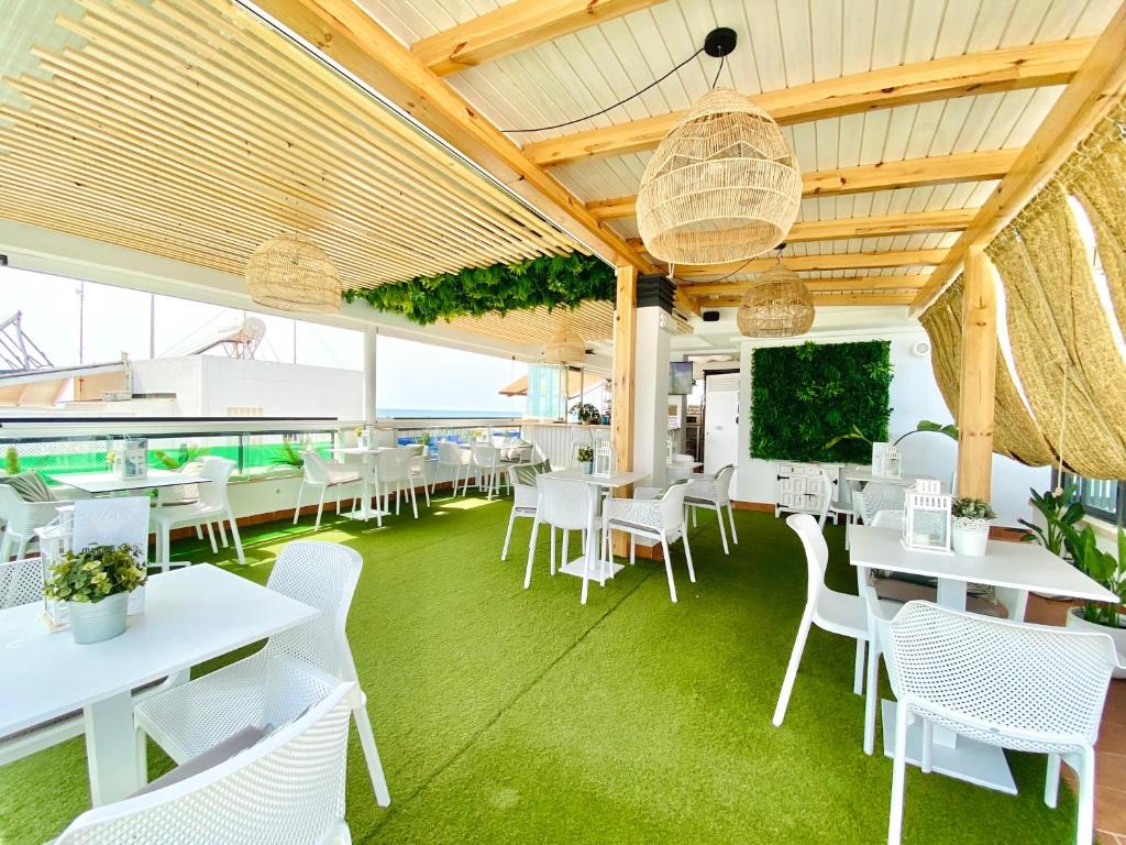 a restaurant with white tables and white chairs at Hotel Apartamentos Marina Luz in Chipiona