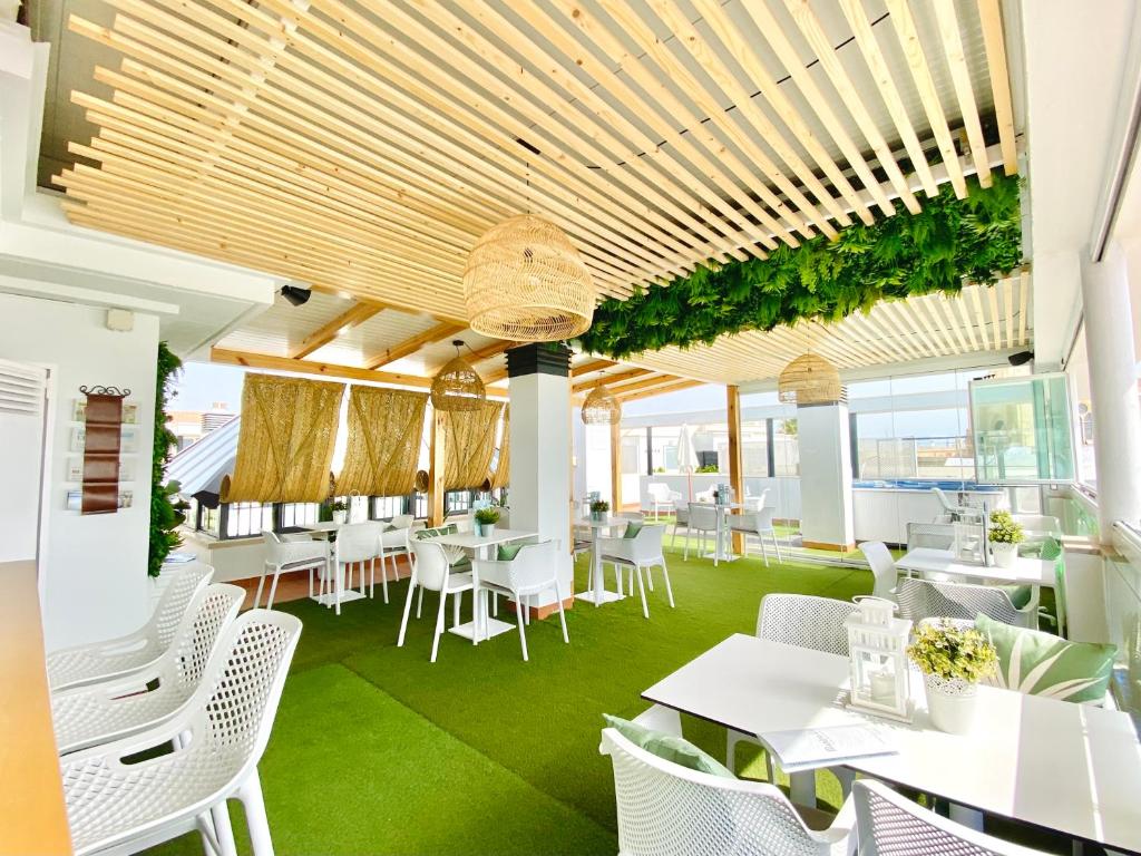 a restaurant with white tables and white chairs at Hotel Apartamentos Marina Luz in Chipiona