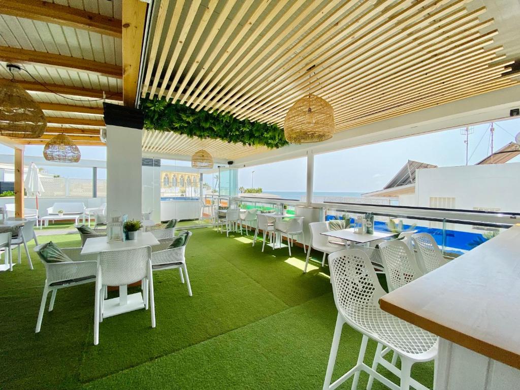 a restaurant with a pool and tables and chairs at Hotel Apartamentos Marina Luz in Chipiona