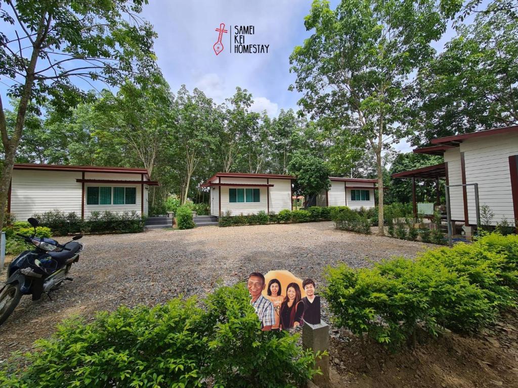 a picture of a family in front of a house at Sameikei Homestay in Phrae