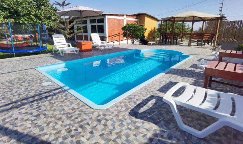 a swimming pool with chairs and a playground at Bungalow Sol del Sur in Paracas
