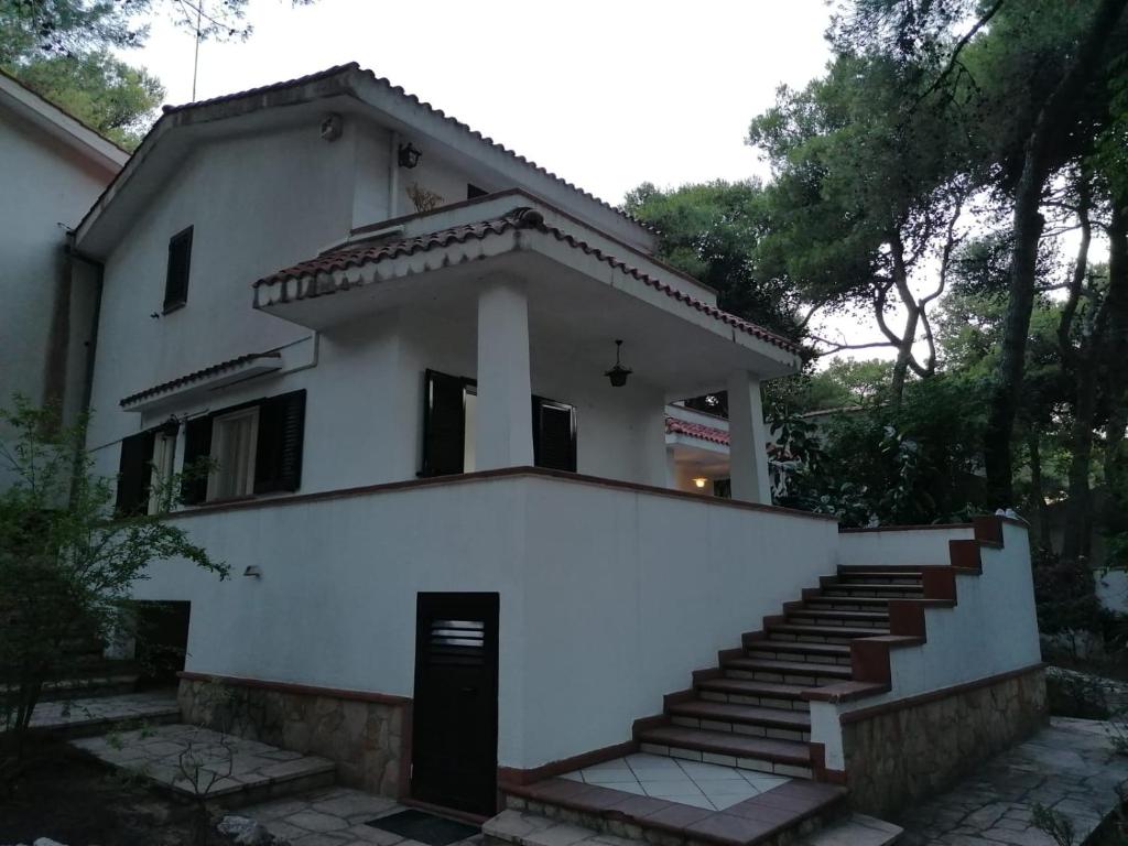 una casa bianca con le scale di fronte di GLADOMUS - Splendida nel cuore della pineta a Pulsano
