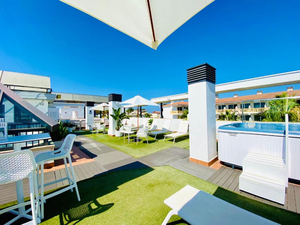 an outdoor patio with chairs and a swimming pool at Hotel Apartamentos Marina Luz in Chipiona