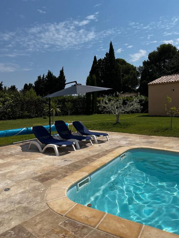 - une piscine avec 2 chaises et un parasol dans l'établissement Magnifique maisonnette Dépendance avec Piscine, à Châteaurenard