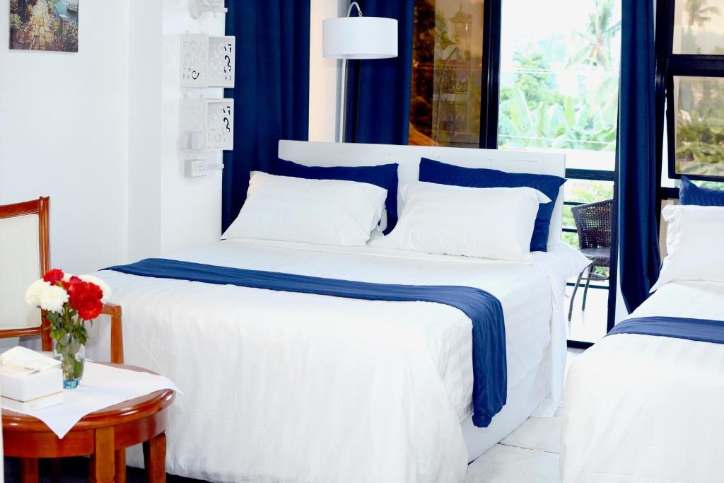 a bedroom with two beds with blue and white sheets at Gmb-Arte' Hotel in Sogod