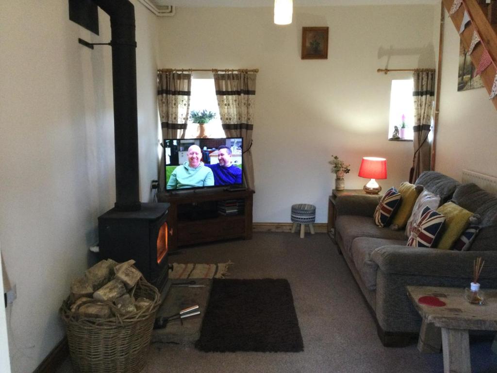 a living room with a couch and a flat screen tv at Cosy Rural Cottage Peak District, Pets Welcome in Hollinsclough