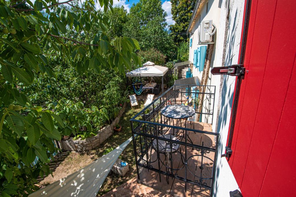 balcón con puerta roja, mesa y sillas en Vrhi Cicarije - Brgudac, Opatija with free parking, en Brgudac