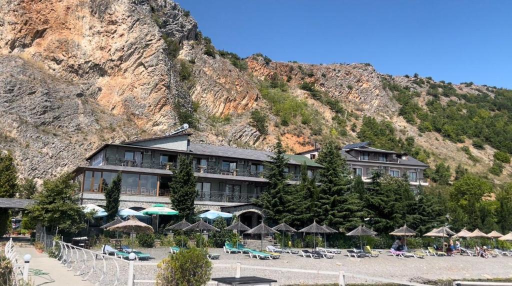 a building with umbrellas in front of a mountain at Kukësi Resort Aldo in Lin