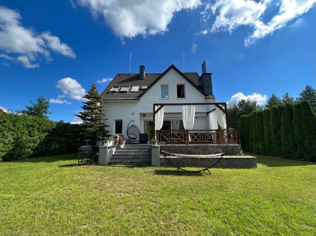 ein weißes Haus mit Hängematte im Hof in der Unterkunft Zakole Brdy in Gostyczyn