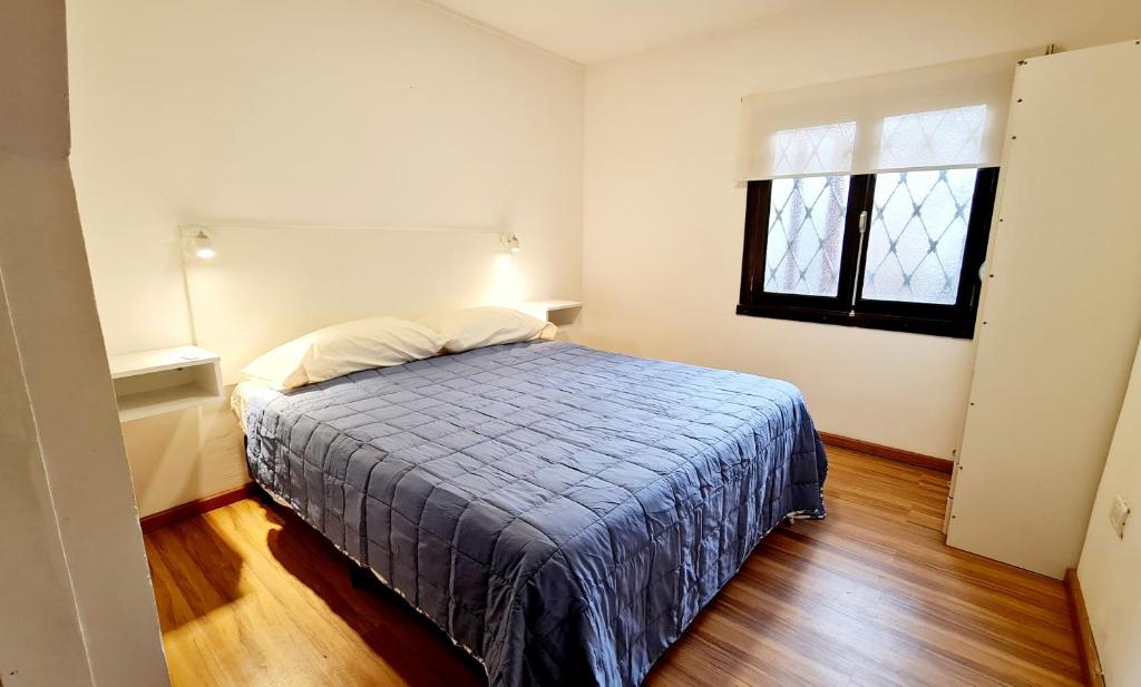 a bedroom with a bed with a blue blanket and a window at Hermosa casa PH equipada y con patio. Aestrenar in Mar del Plata