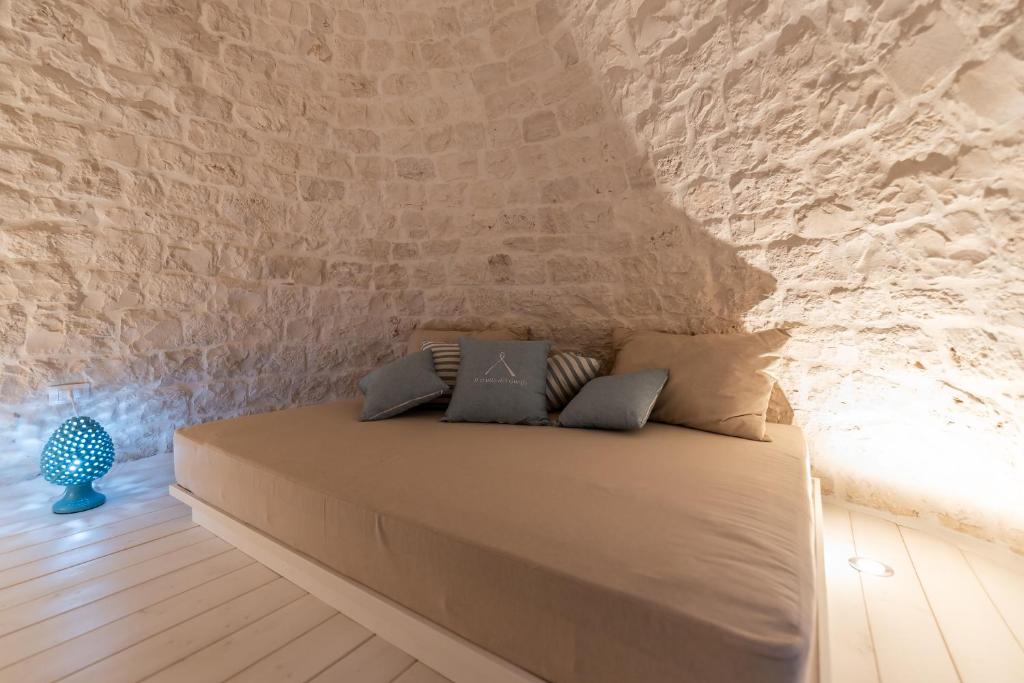 Cama en habitación con pared de piedra en Il trullo del Guelfo en Alberobello