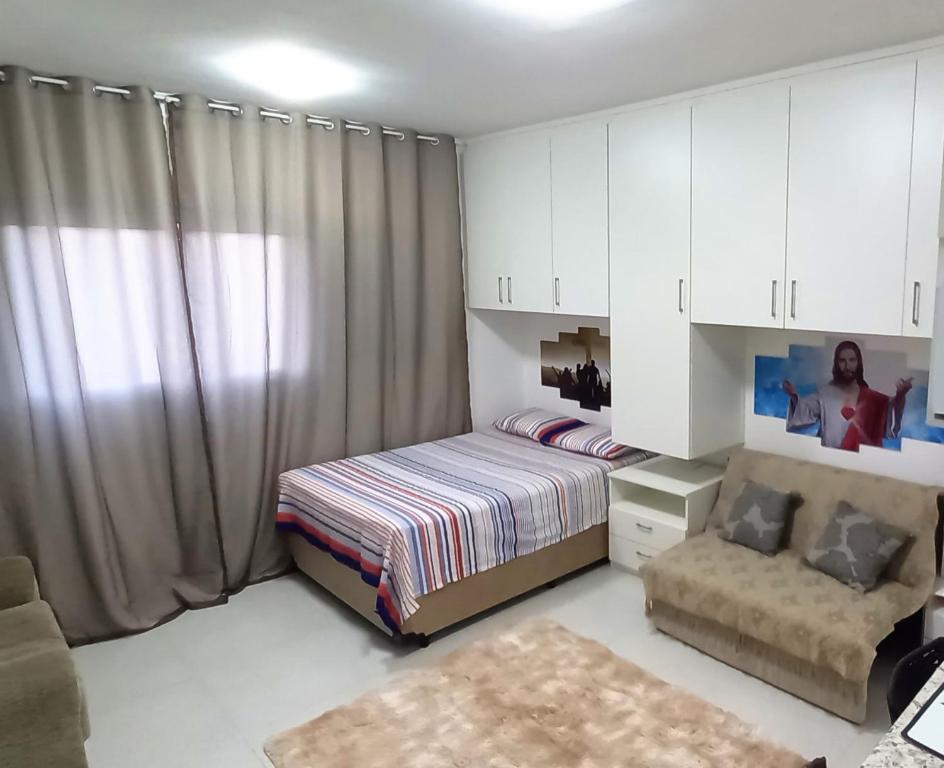 1 dormitorio con 1 cama y 1 silla en Apto Canção Nova - Condomínio da Fé, en Cachoeira Paulista
