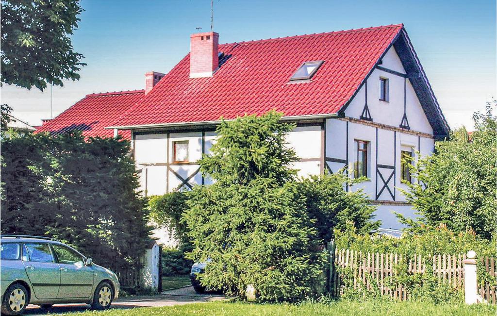 a house with a red roof with a car parked in front at Beautiful Home In Darlowo With 3 Bedrooms in Darłowo