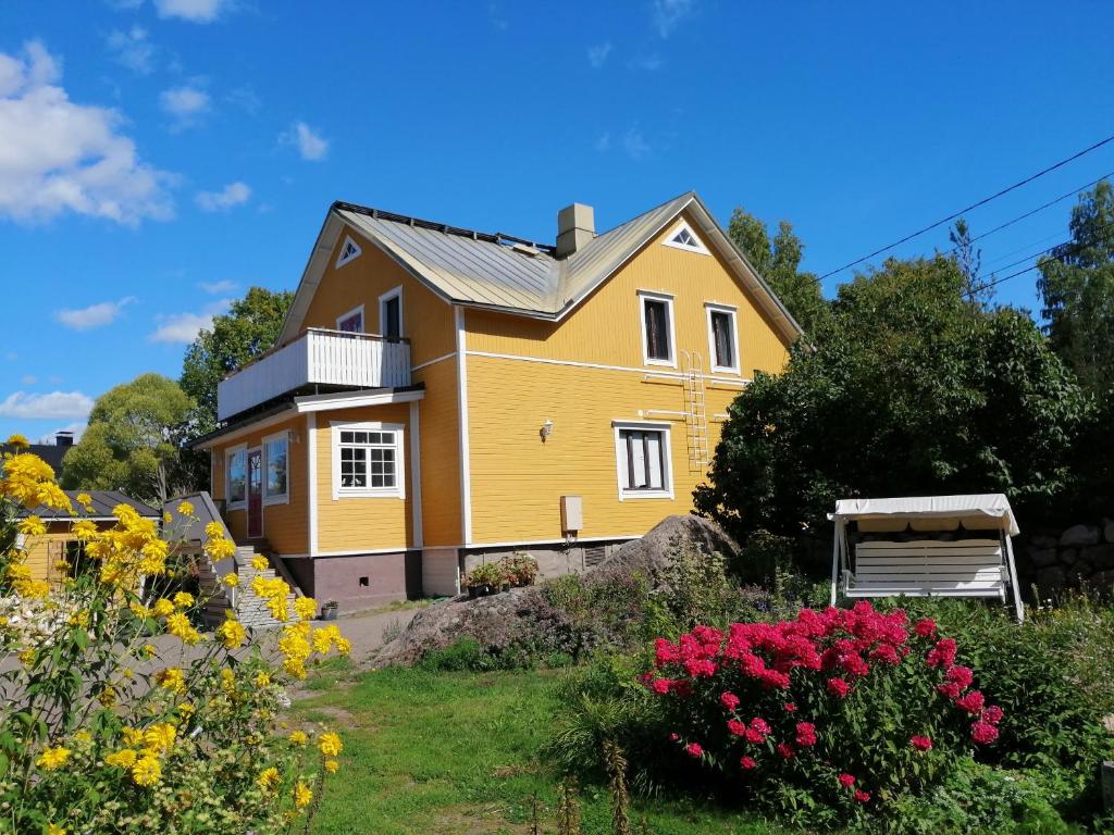 una casa amarilla con flores en el patio en Guesthouse Lokinlaulu en Kotka