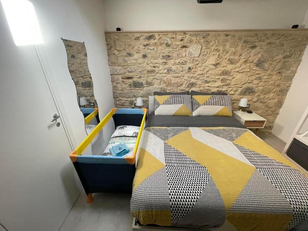 1 dormitorio con cama y pared de piedra en Chista é a Zita!!, en Ragusa