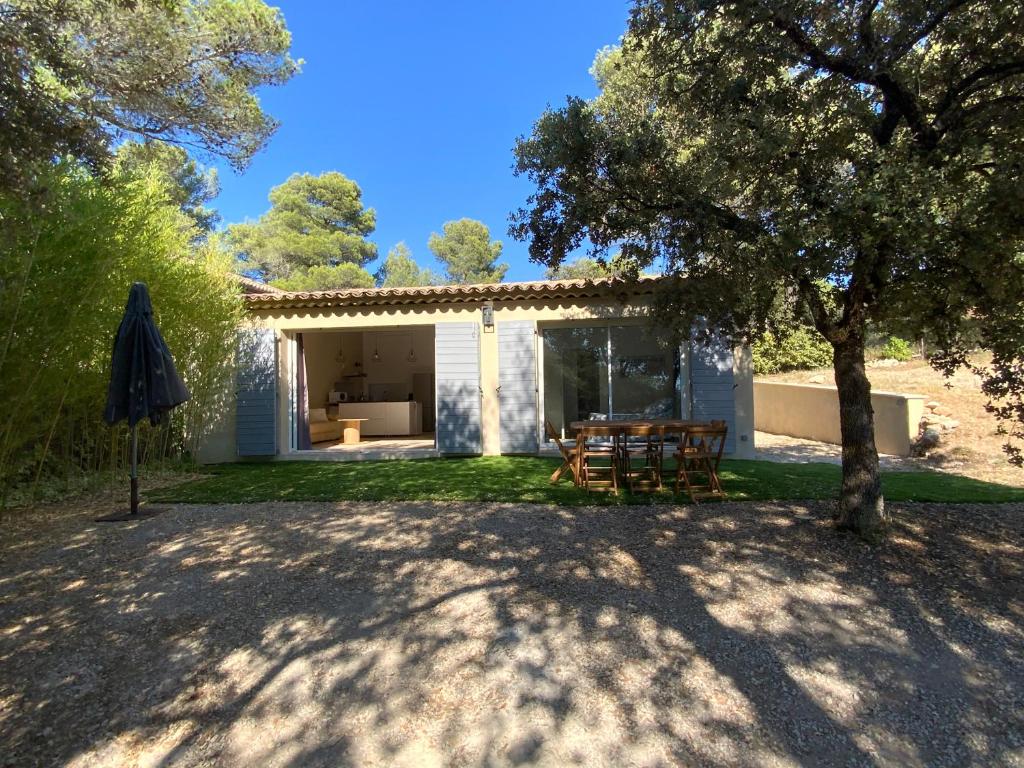een huis met een tafel en een boom in de tuin bij Maison au calme au pied du luberon in La Bastide-des-Jourdans