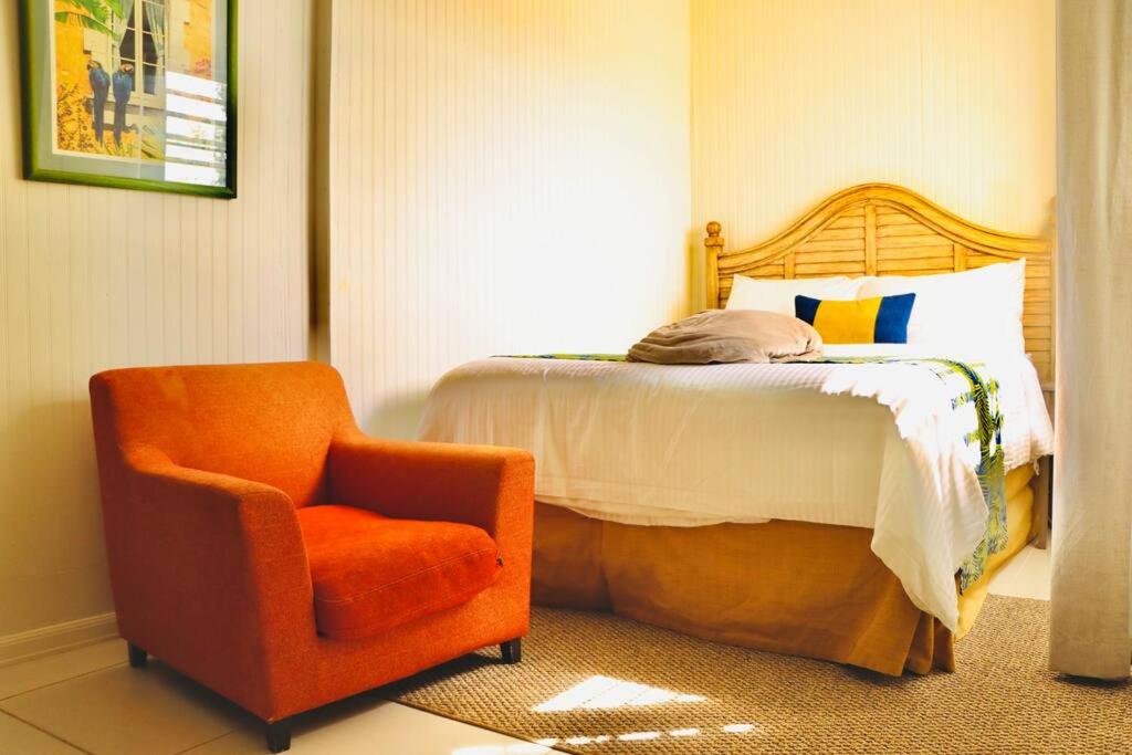 a bedroom with a bed and an orange chair at The Northside Cottage in Nazareth