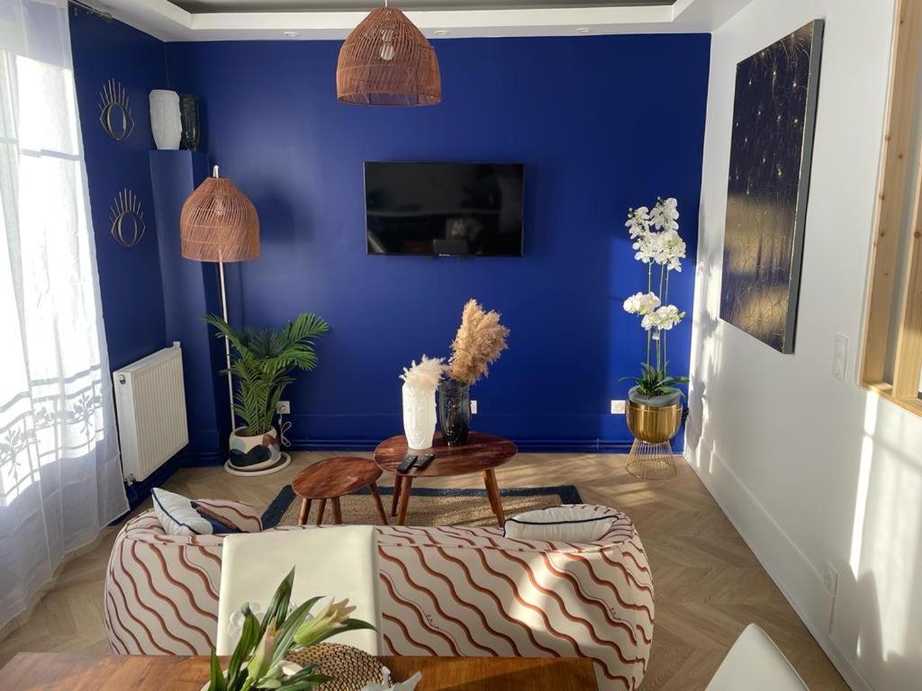 un salon avec un mur bleu et une table dans l'établissement L'AMAZONIE - Lovely apartment near to the train station and Orly Airport, à Juvisy-sur-Orge