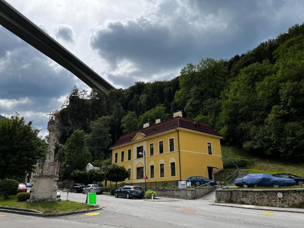 um edifício amarelo num parque de estacionamento ao lado de uma montanha em Palma Apartment em Schottwien