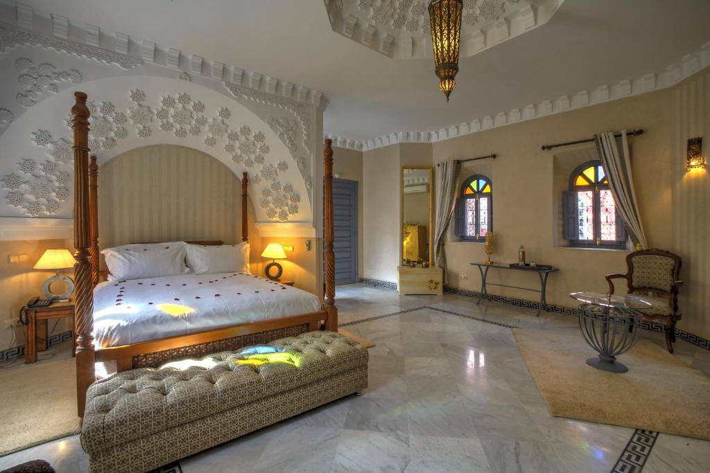 a bedroom with a bed and a table and windows at Ksar Anika Boutique Hotel & Spa in Marrakech