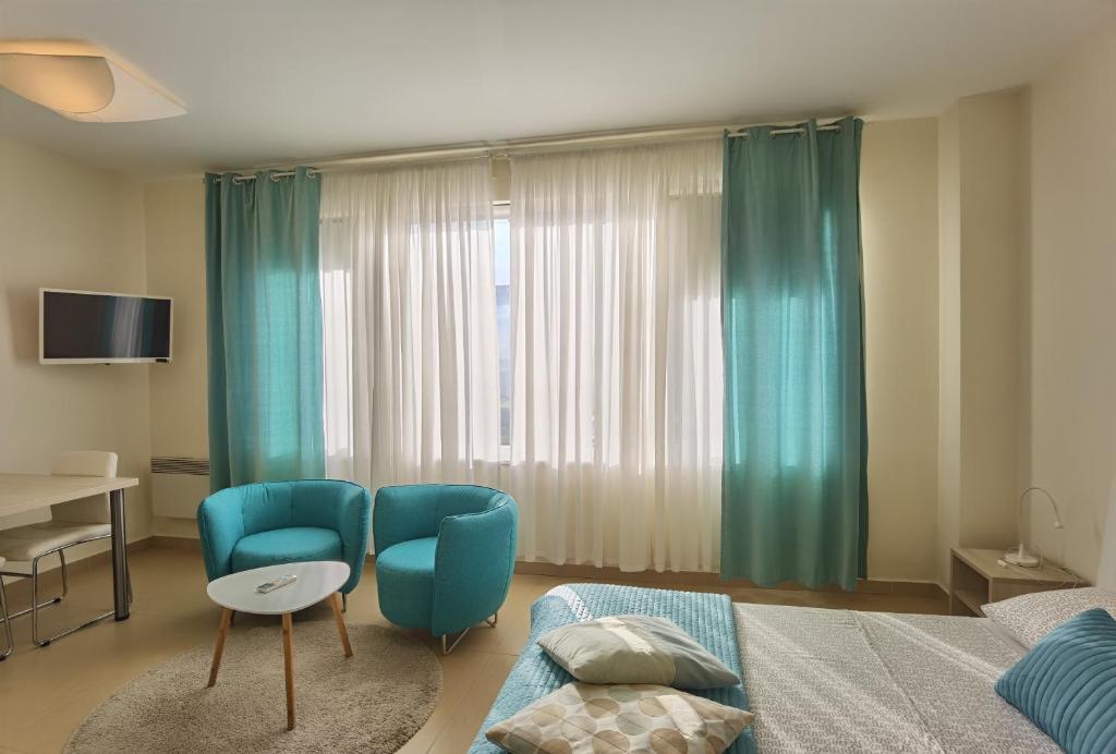 a bedroom with a bed and two chairs and a table at Cuvi Studio S in Rovinj