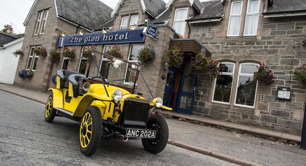 an old yellow car parked in front of a building at The Glen Hotel Newtonmore in Newtonmore