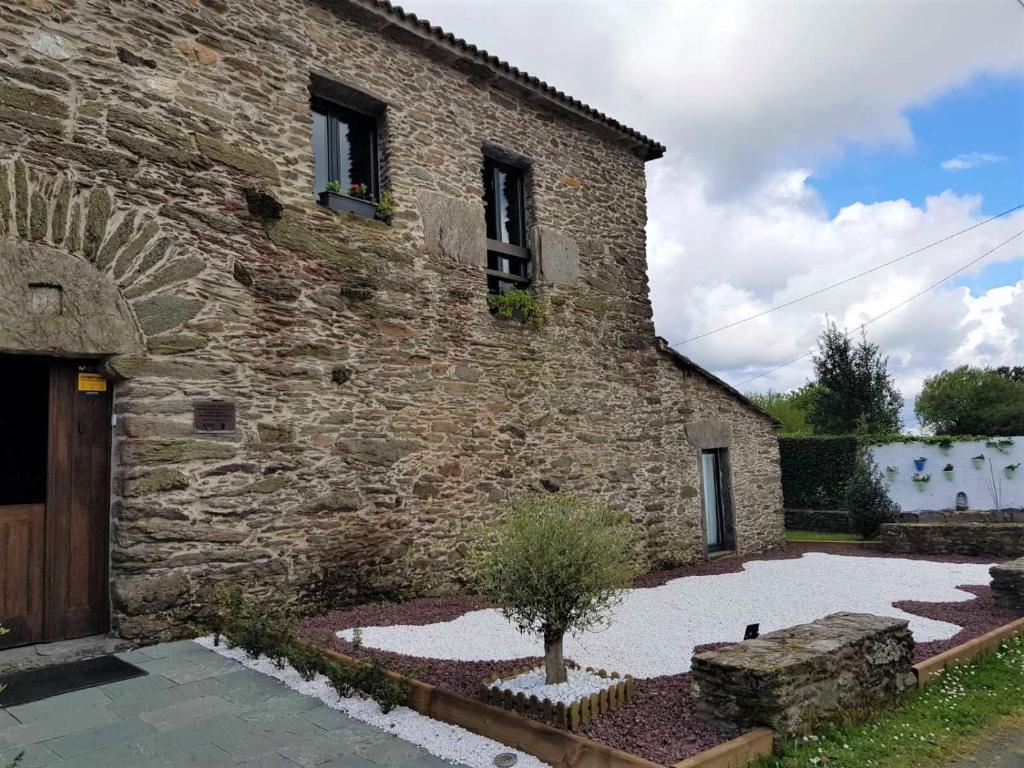 un edificio de piedra con un árbol delante de él en Lar da Mota Boutique Hotel, en Arzúa