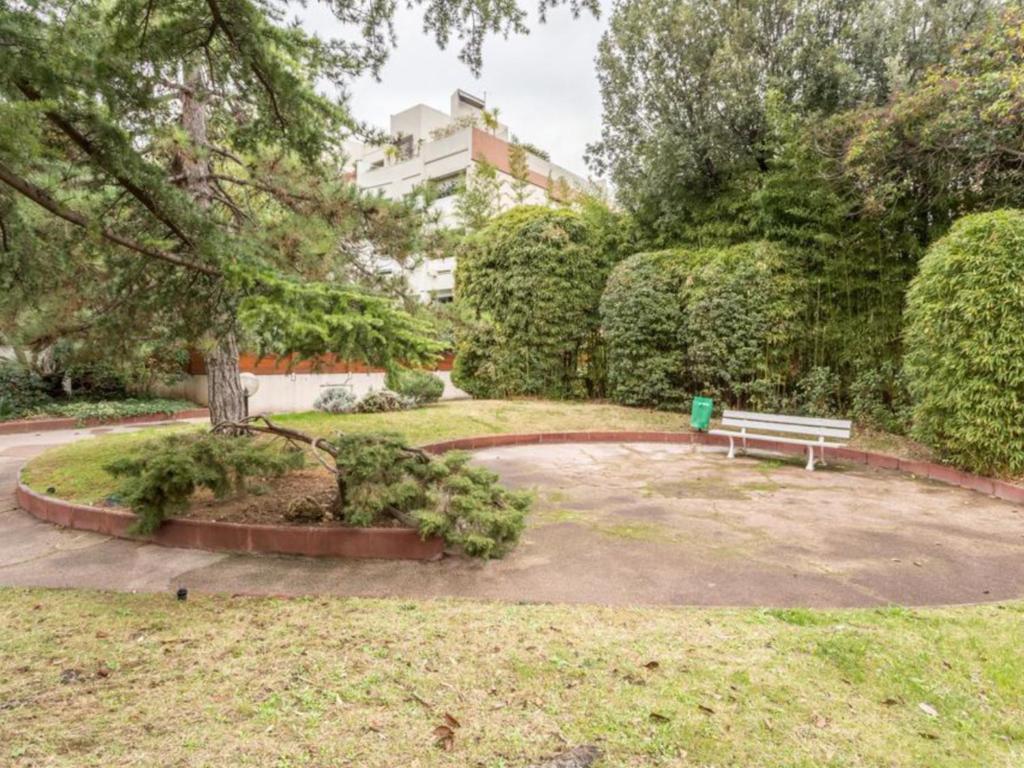 een park met een bank en bomen en een gebouw bij Les jardins du Paradis in Marseille