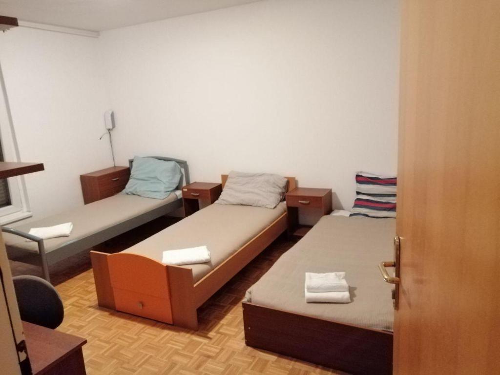 Habitación con 2 camas, silla y puerta en Arena stožice rooms, en Liubliana