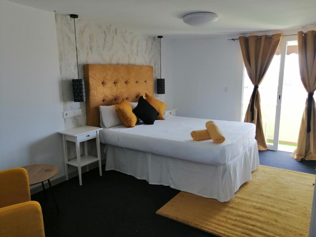 a bedroom with a large white bed with yellow pillows at Chabela's water wall in La Lajita
