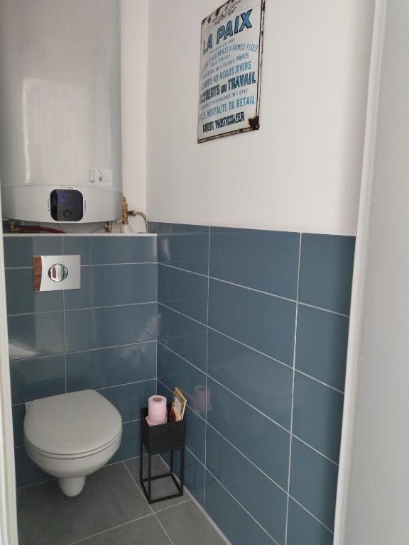 a bathroom with a toilet and a blue tile wall at La Petite Florentine in Saint-Florent-le-Vieil