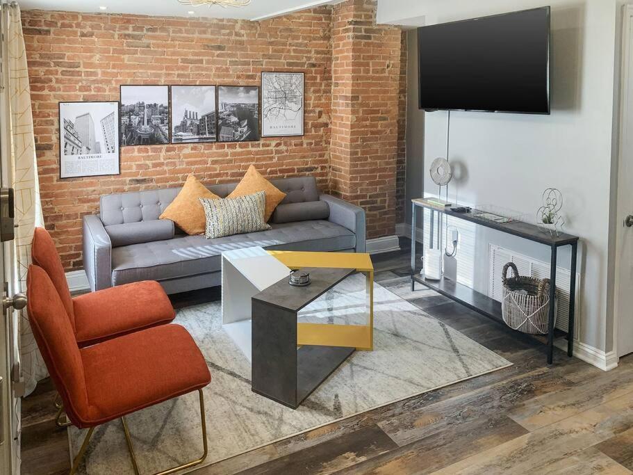 a living room with a couch and a brick wall at Cozy Modern Apt in the Heart of Fells Point! in Baltimore