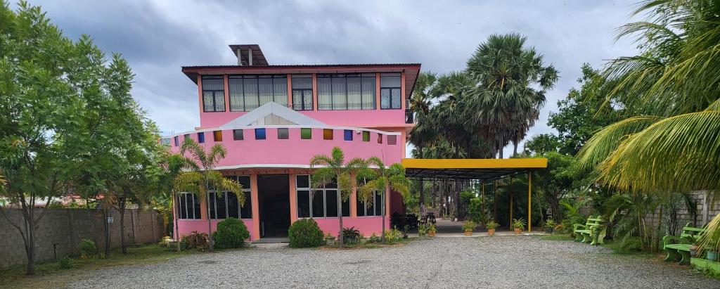 a pink building with a largeventh floor at Gnanam Holiday Inn in Pasikuda