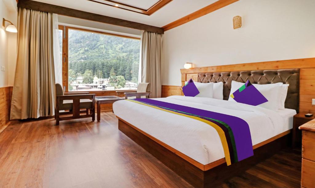 a bedroom with a bed and a large window at Treebo Tryst Sattva With Mountain View in Manāli
