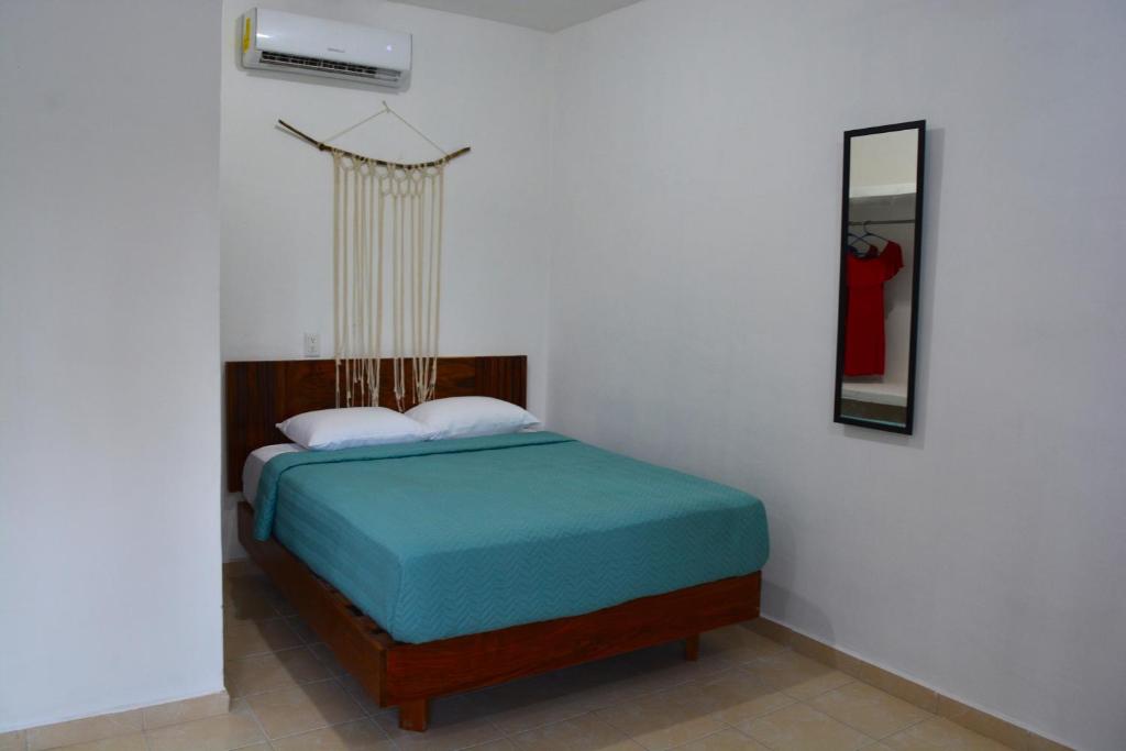 ein Schlafzimmer mit einem Bett mit einer blauen Decke und einem Spiegel in der Unterkunft Xula Bacalar in Bacalar