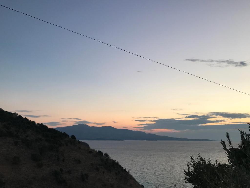 a sunset over the water with a hill at Vila Bedro in Sarandë