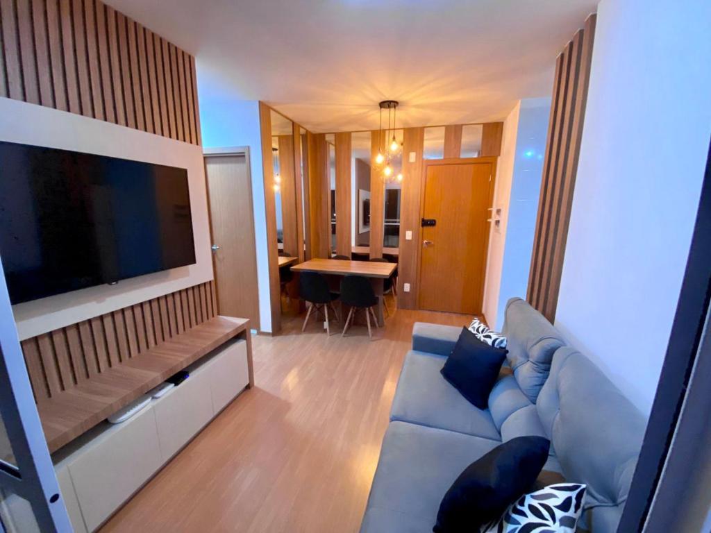 a living room with a blue couch and a television at Apartamento com Sacada na Gleba, Novo e equipado in Londrina