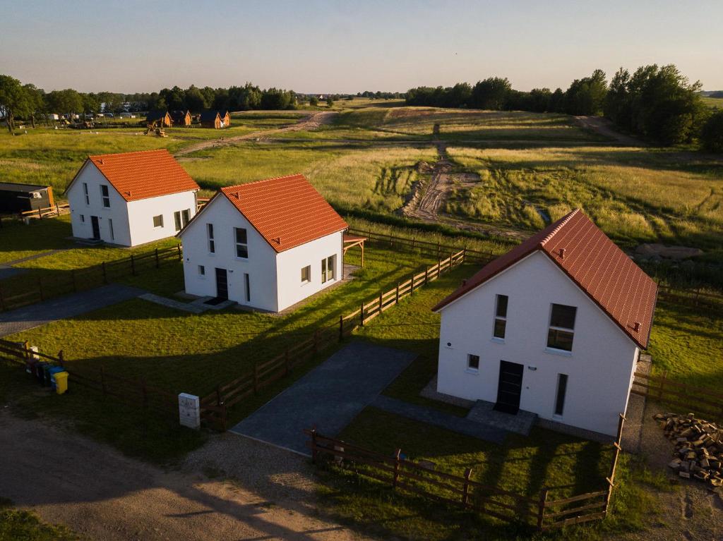 tres casas blancas con techos naranjas en un campo en Mazury Zakątek Salpia 1 dom apartament 10 osób Family 1, en Prażmowo