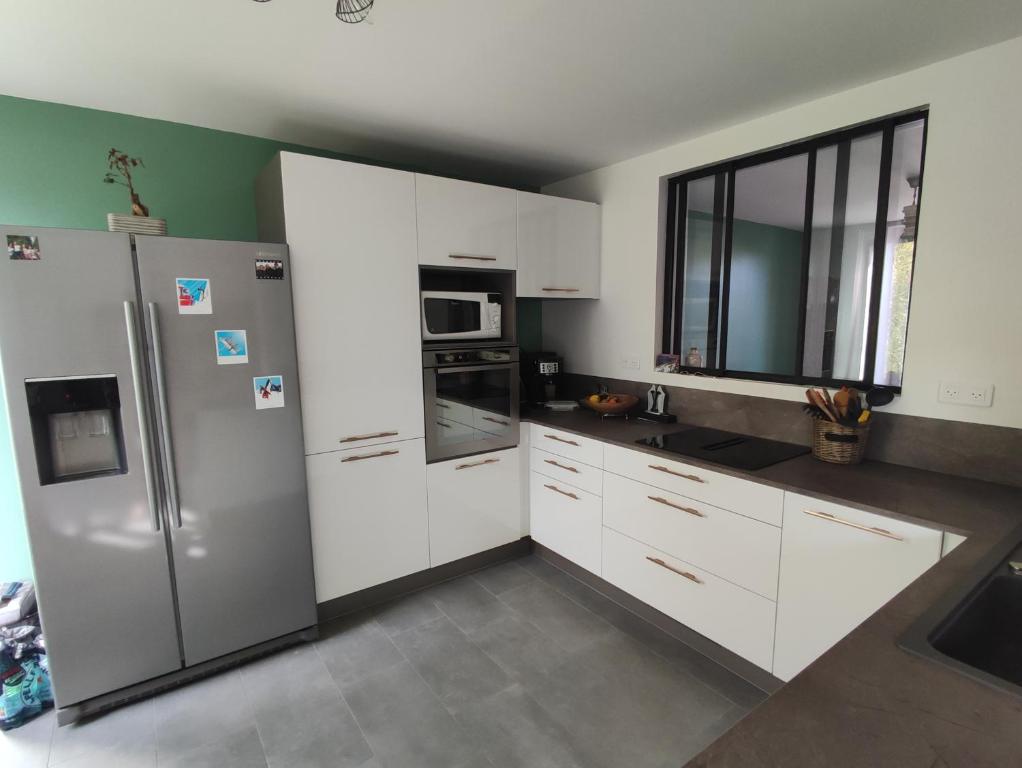 a kitchen with white cabinets and a refrigerator at Nancy - Maison chaleureuse in Champigneulles