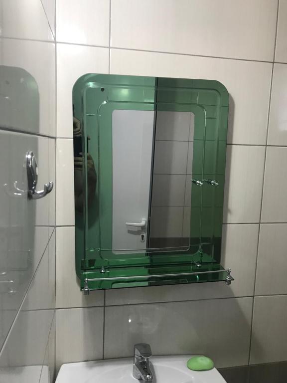 a bathroom with a green mirror and a sink at Vila Bedro in Sarandë
