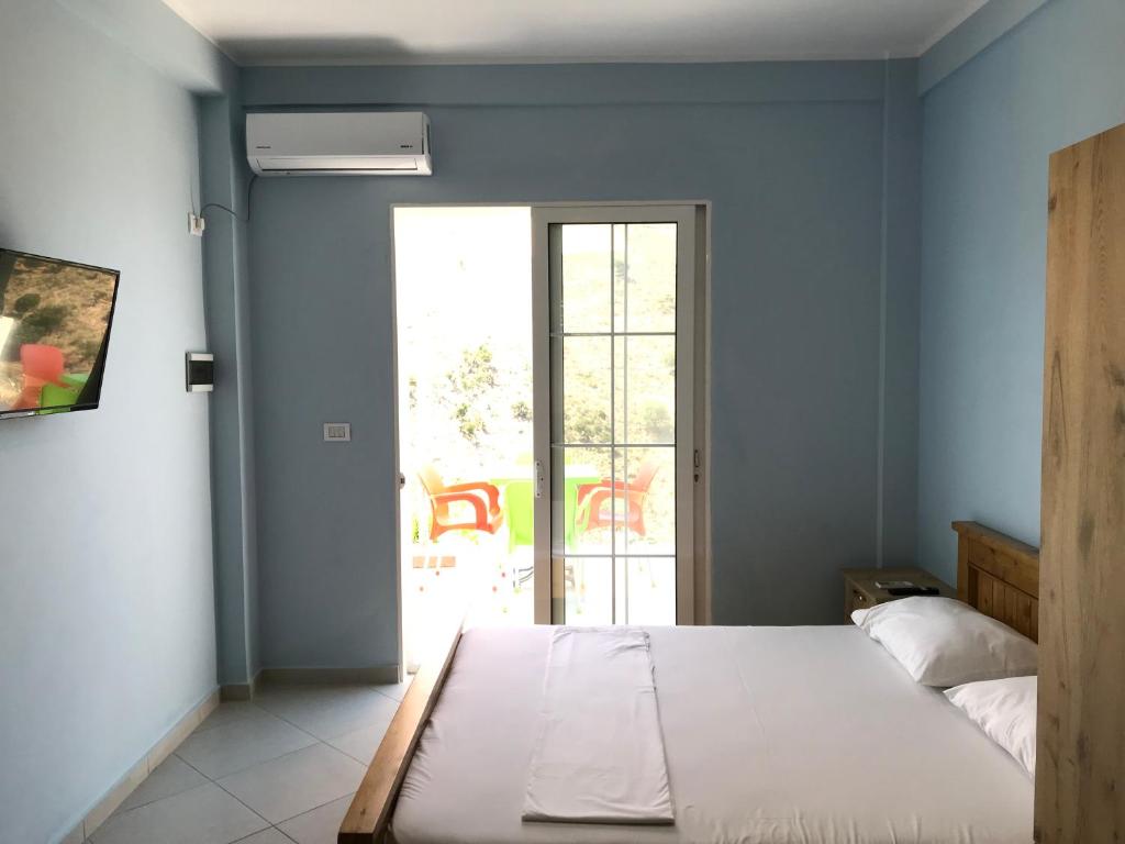 a bedroom with a bed and a door to a patio at Vila Bedro in Sarandë